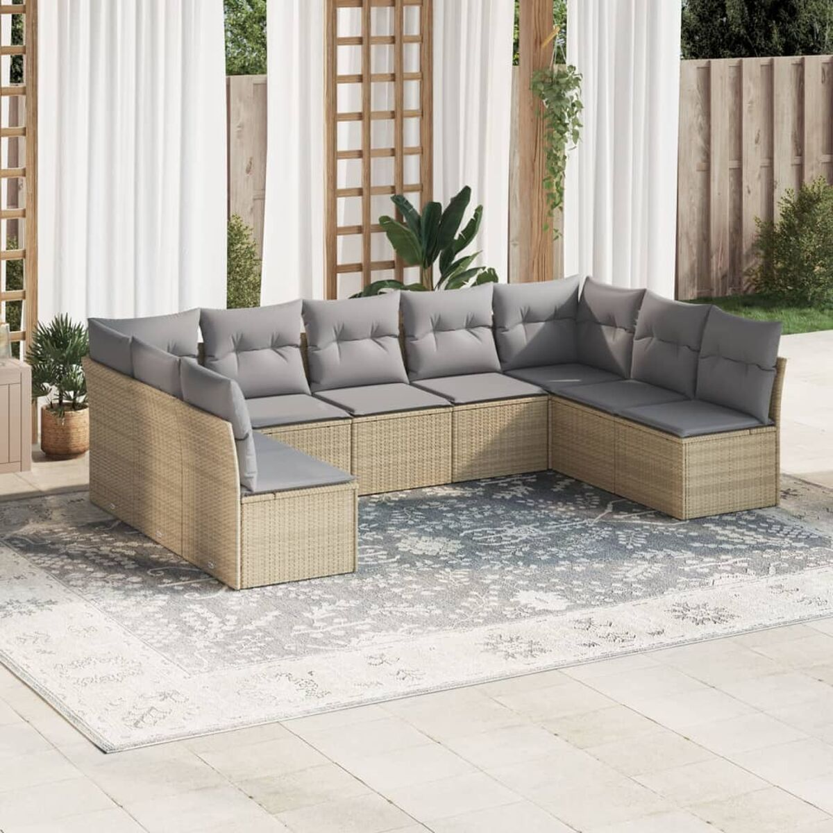 Ecksofa aus Rattan mit grauen Kissen auf einem Teppich im Terrassenbereich.