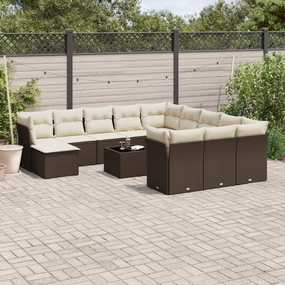 Set divano da esterno in vimini marrone scuro con cuscini beige. Un tavolino al centro.
