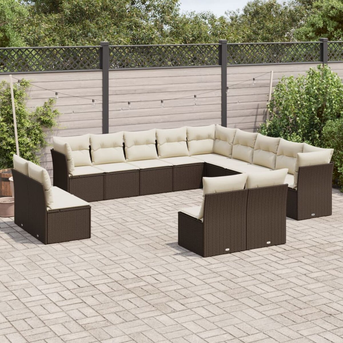 Braunes Outdoor-Ecksofa aus Rattan mit beigen Kissen auf einer Ziegelterrasse, U-förmig angeordnet.