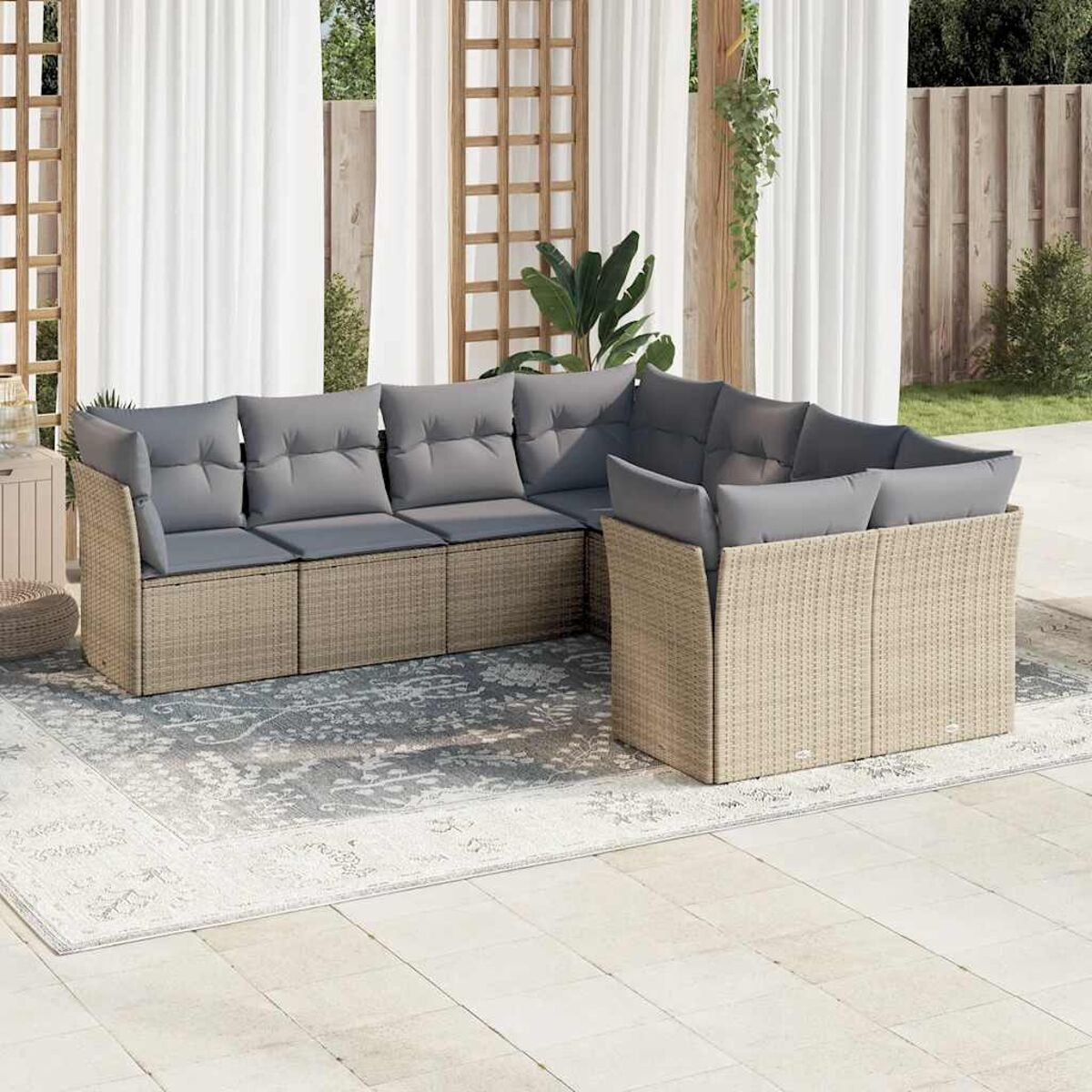 Ecksofa im Freien mit grauen Kissen auf einem gemusterten Teppich. Hintergrund ist ein Holzzaun.