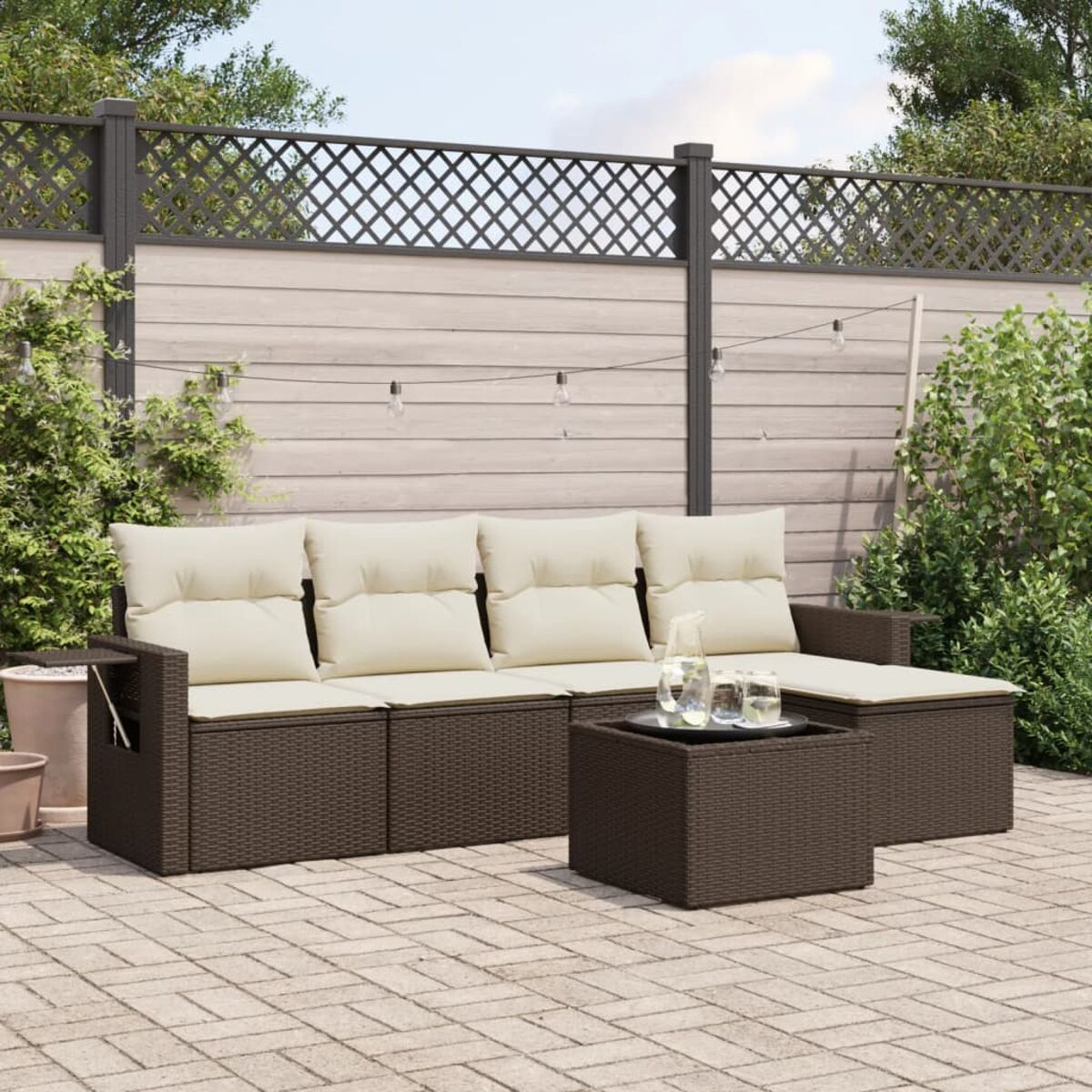 Divano componibile in rattan marrone con cuscini bianchi e tavolino, patio.