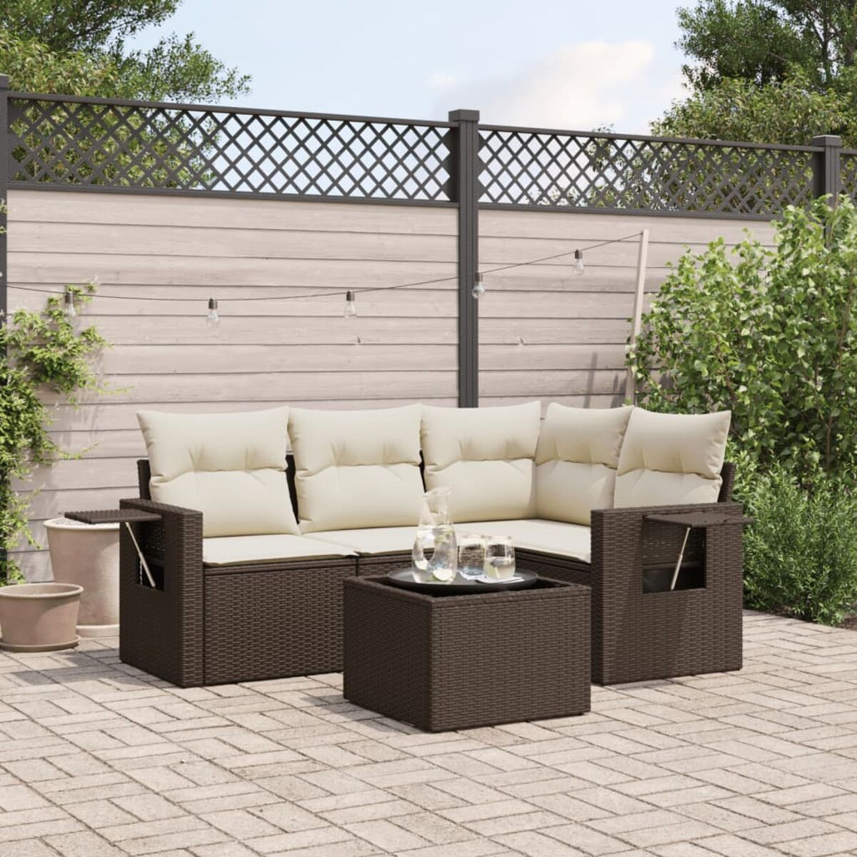 Un set da patio con divano e tavolo, vimini marrone e cuscini color crema.