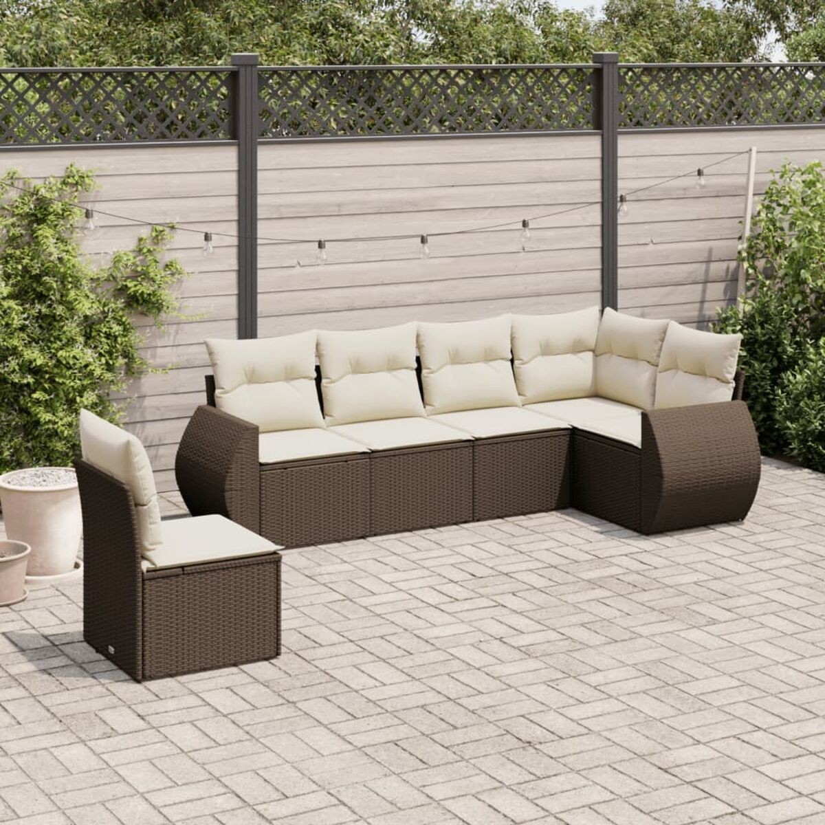Set da esterno in vimini marrone con cuscini beige su un patio. Una sedia è accanto al divano.