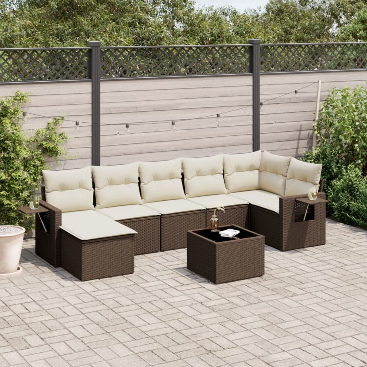 Set divano in rattan su un patio. Include divano angolare, sedia e tavolo con cuscini.