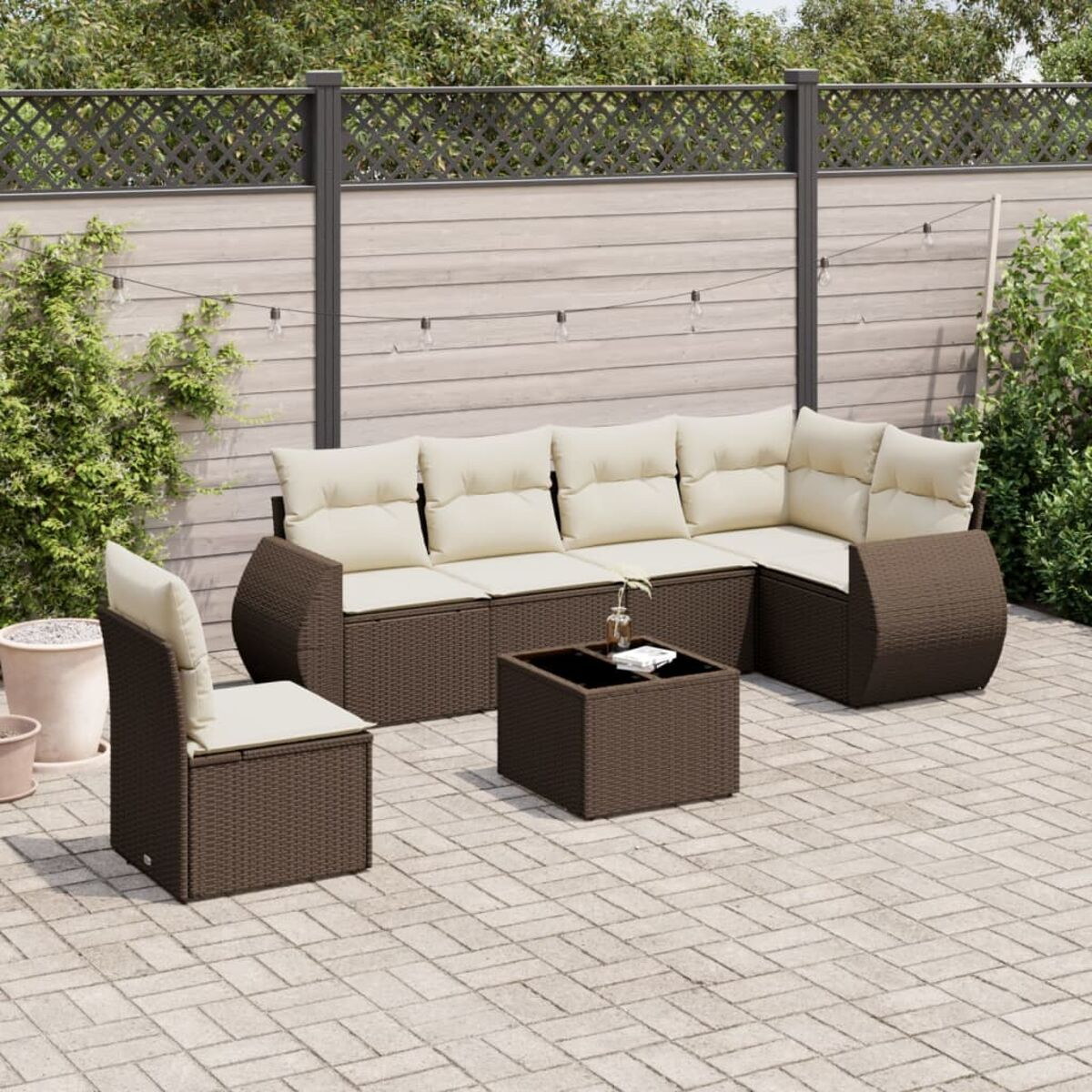 Sofá seccional de exterior de ratán marrón con cojines beige y una mesa de centro en un patio.