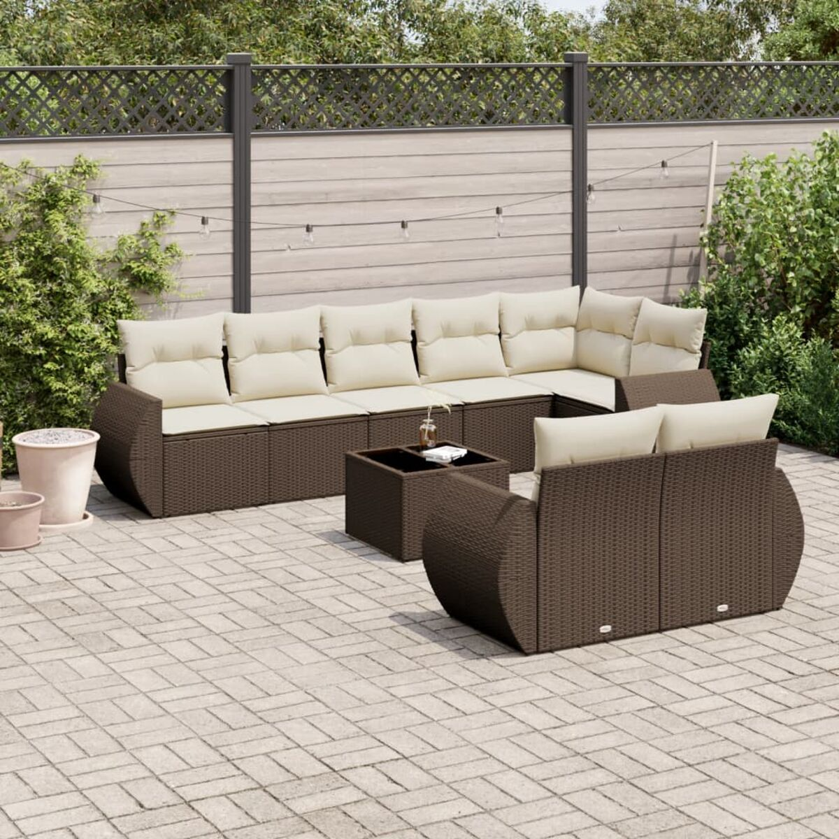Braunes Outdoor-Sofaset aus Korbgeflecht mit beigen Kissen und einem quadratischen Tisch auf einer Terrasse.