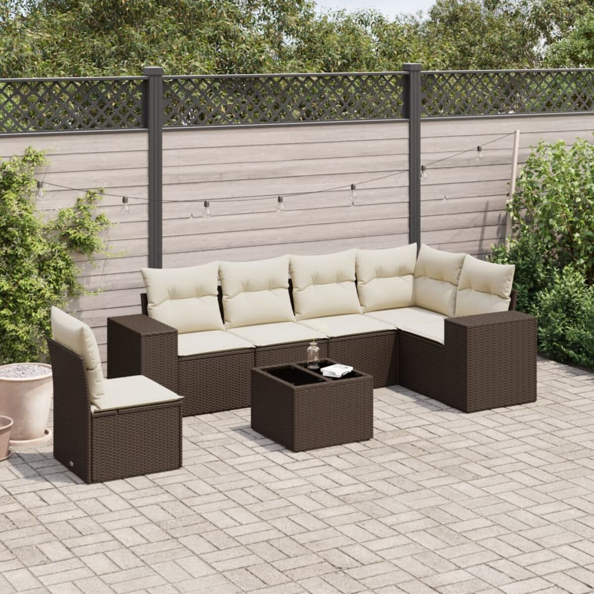 Set da patio in rattan marrone con cuscini beige su un patio in mattoni. Include divano, sedia e tavolo.