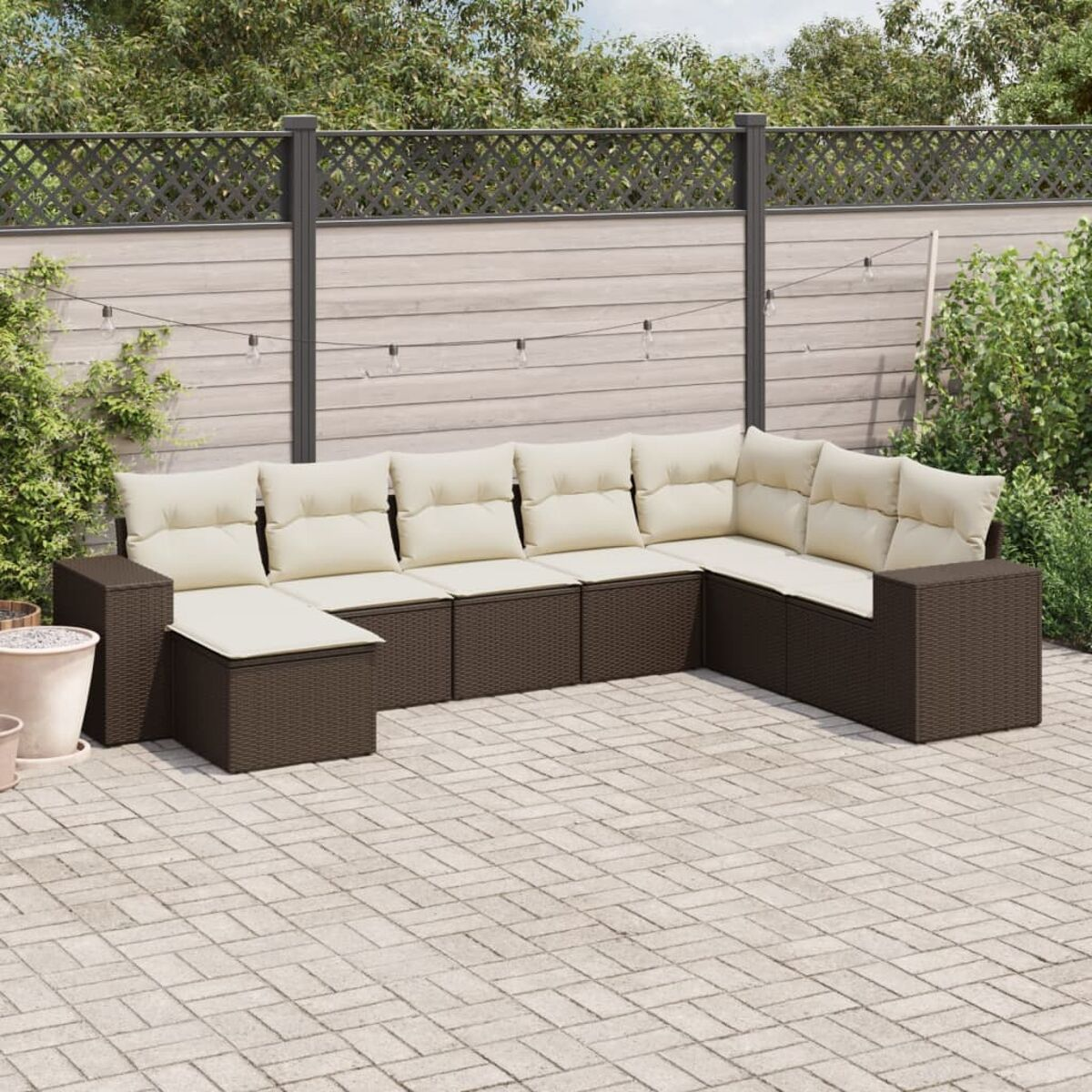 Divano angolare da esterno marrone e beige con cuscini beige, su un patio in mattoni.