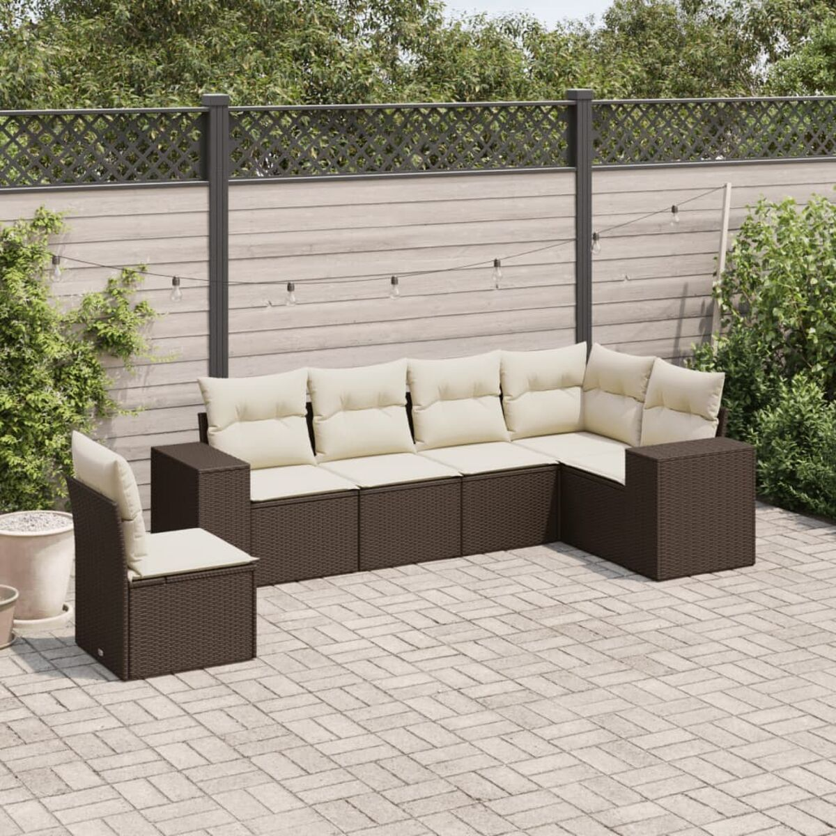 Ein braunes Outdoor-Ecksofa aus Korbgeflecht mit beigen Kissen und einem Einzelstuhl auf einer Terrasse.
