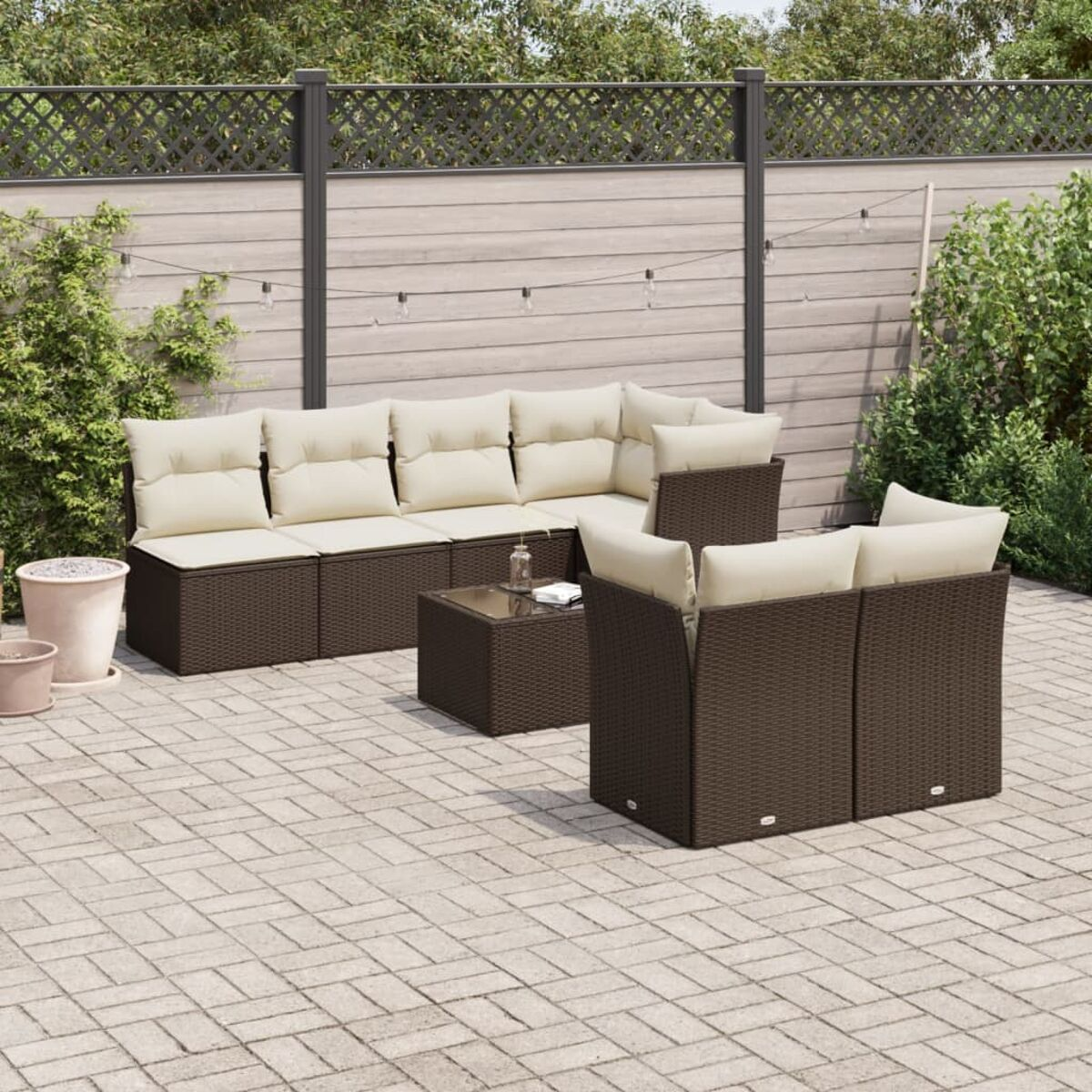 Set da patio esterno con mobili in vimini marroni. Cuscini beige. Patio in mattoni.