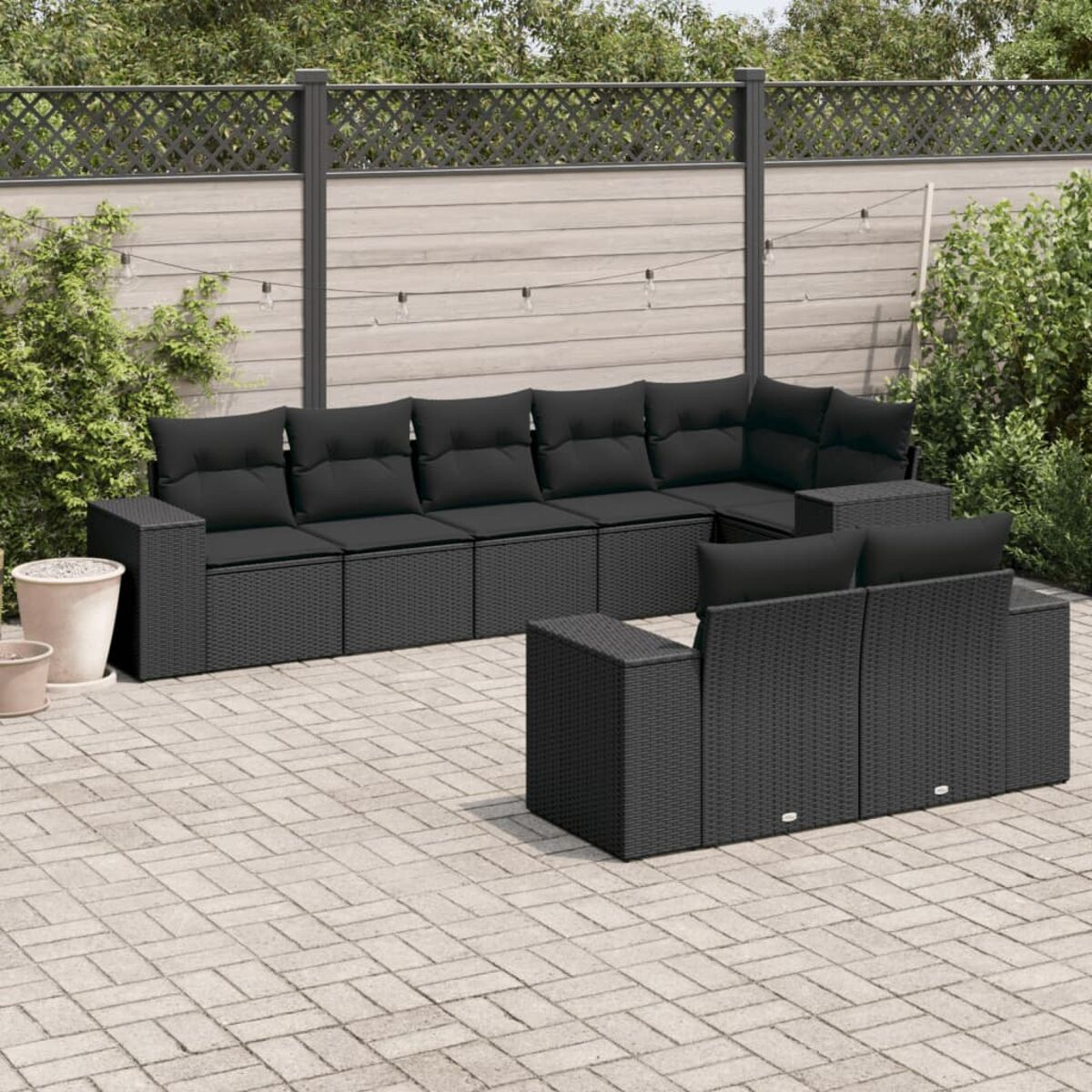 Schwarzes Outdoor-Rattan-Ecksofa mit schwarzen Kissen, kleiner Couchtisch auf einer Terrasse.