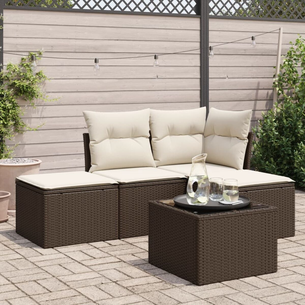 Set di mobili da esterno in vimini marrone scuro. Divano, pouf e tavolo. Patio con bevande.