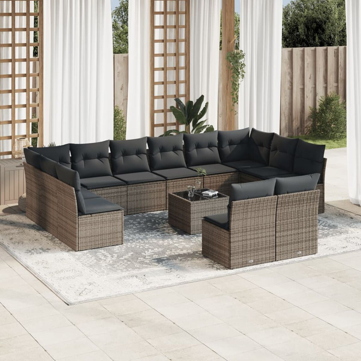Outdoor-Ecksofa aus Korbgeflecht mit dunkelgrauen Kissen, auf gemustertem Teppich, mit Couchtisch.
