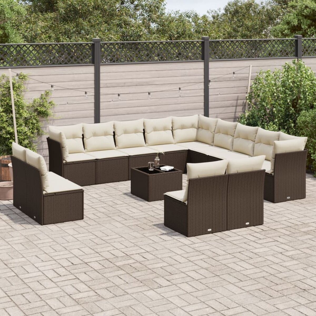 Set divano angolare da esterno con vimini marrone scuro, cuscini beige e un tavolo.