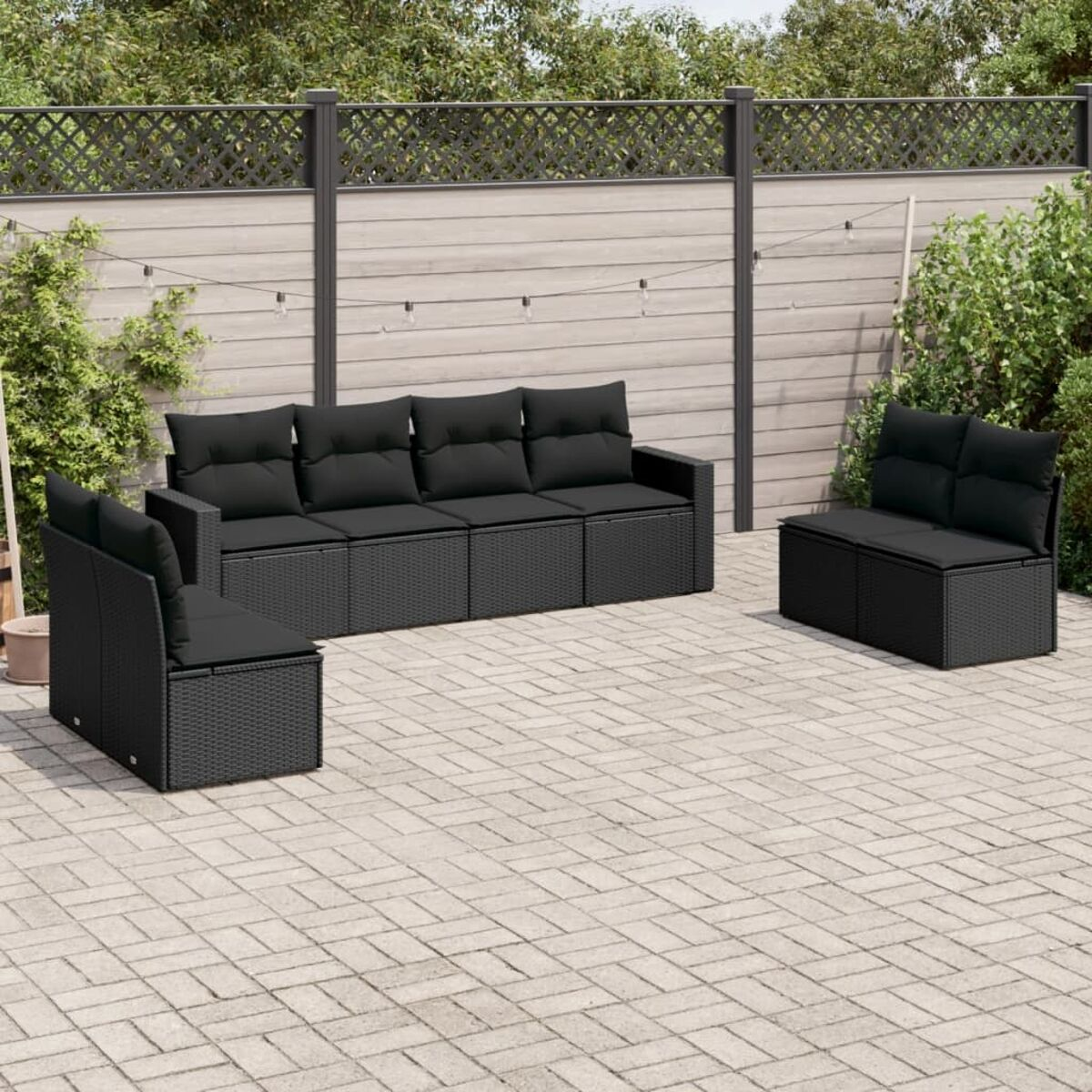 Schwarzes Outdoor-Rattan-Sofaset mit schwarzen Kissen, auf einer Ziegelterrasse.