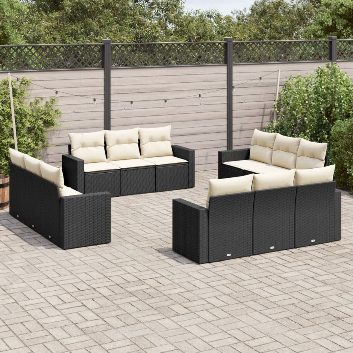 Outdoor-Set aus schwarzem Korbmöbeln mit cremefarbenen Kissen und einer Ziegelterrasse.