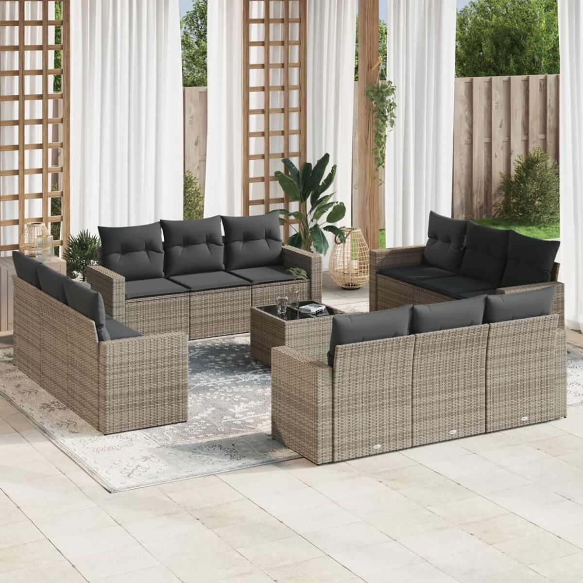 Terrasseneinrichtung: mehrere Korbsitzgruppen, schwarze Kissen, Teppich, Couchtisch. Tag.