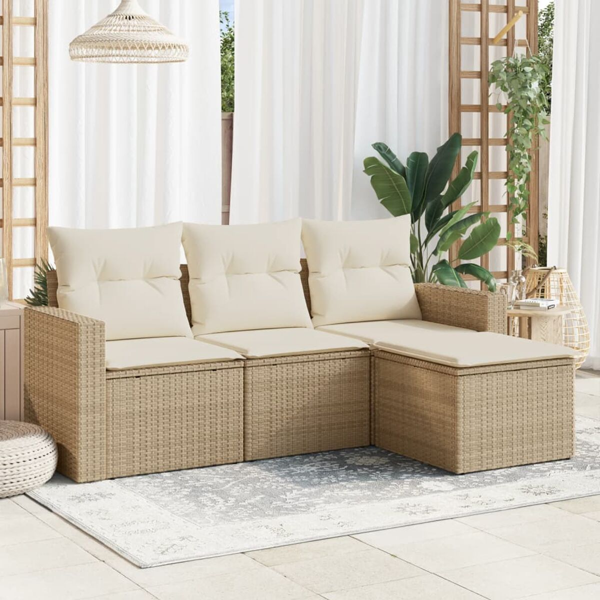Ein beiges Korbbettsofa mit weißen Kissen auf einer Terrasse. Ein gemusterter Teppich davor.