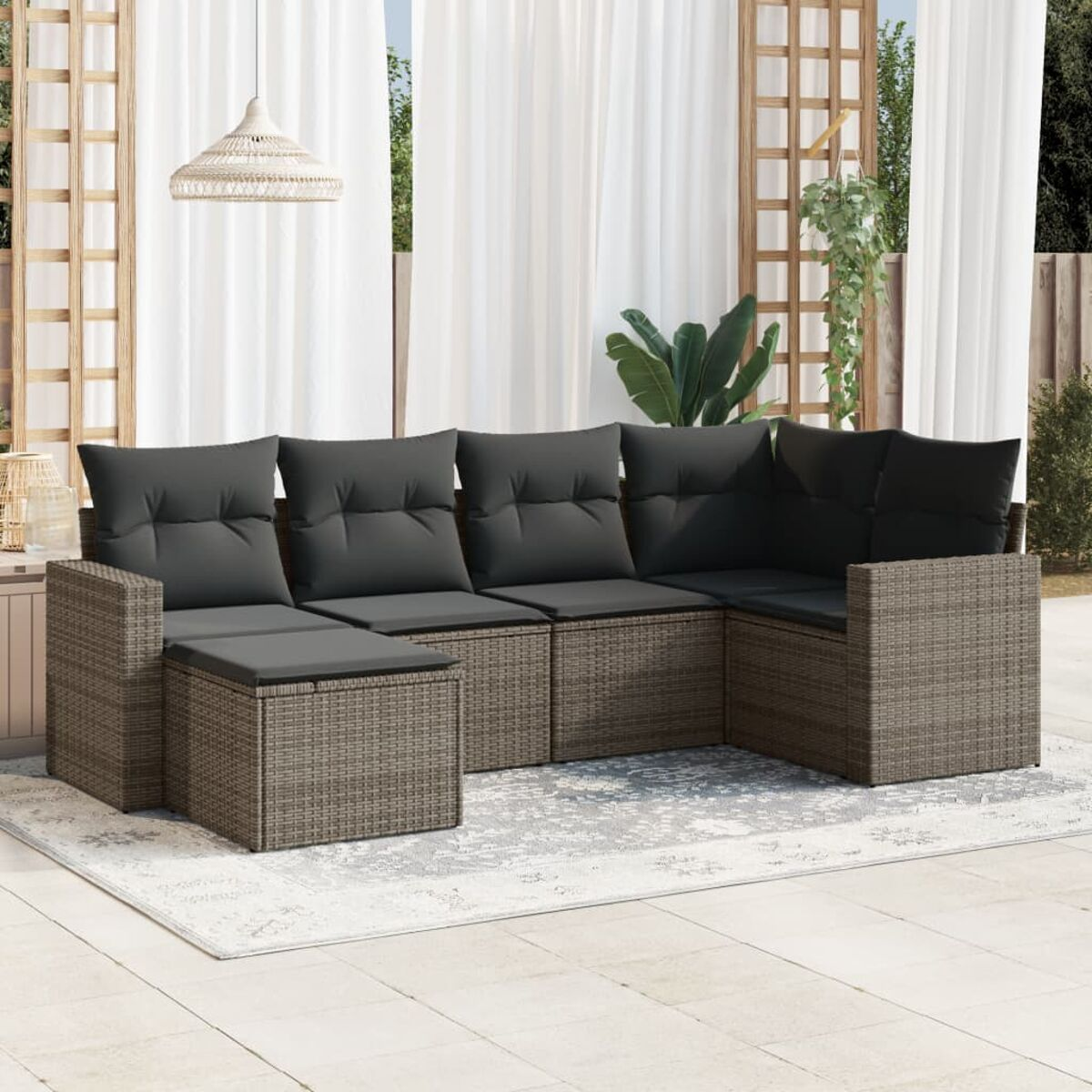 Gartenmöbel-Set aus Korbgeflecht mit dunkelgrauen Kissen, Teppich und weißen Vorhängen.