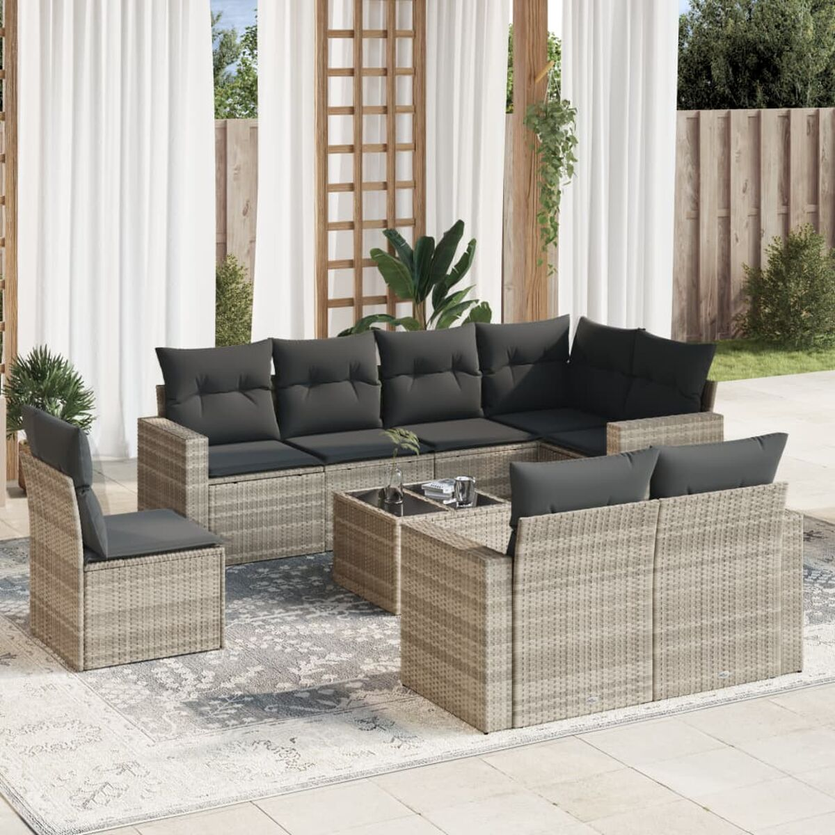 Outdoor-Ecksofa mit grauen Kissen und einem Couchtisch. Das Set steht auf einem gemusterten Teppich.