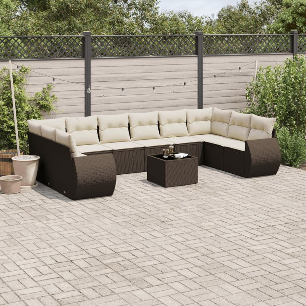 Set divano da esterno in rattan marrone con cuscini color crema e tavolo su un patio.