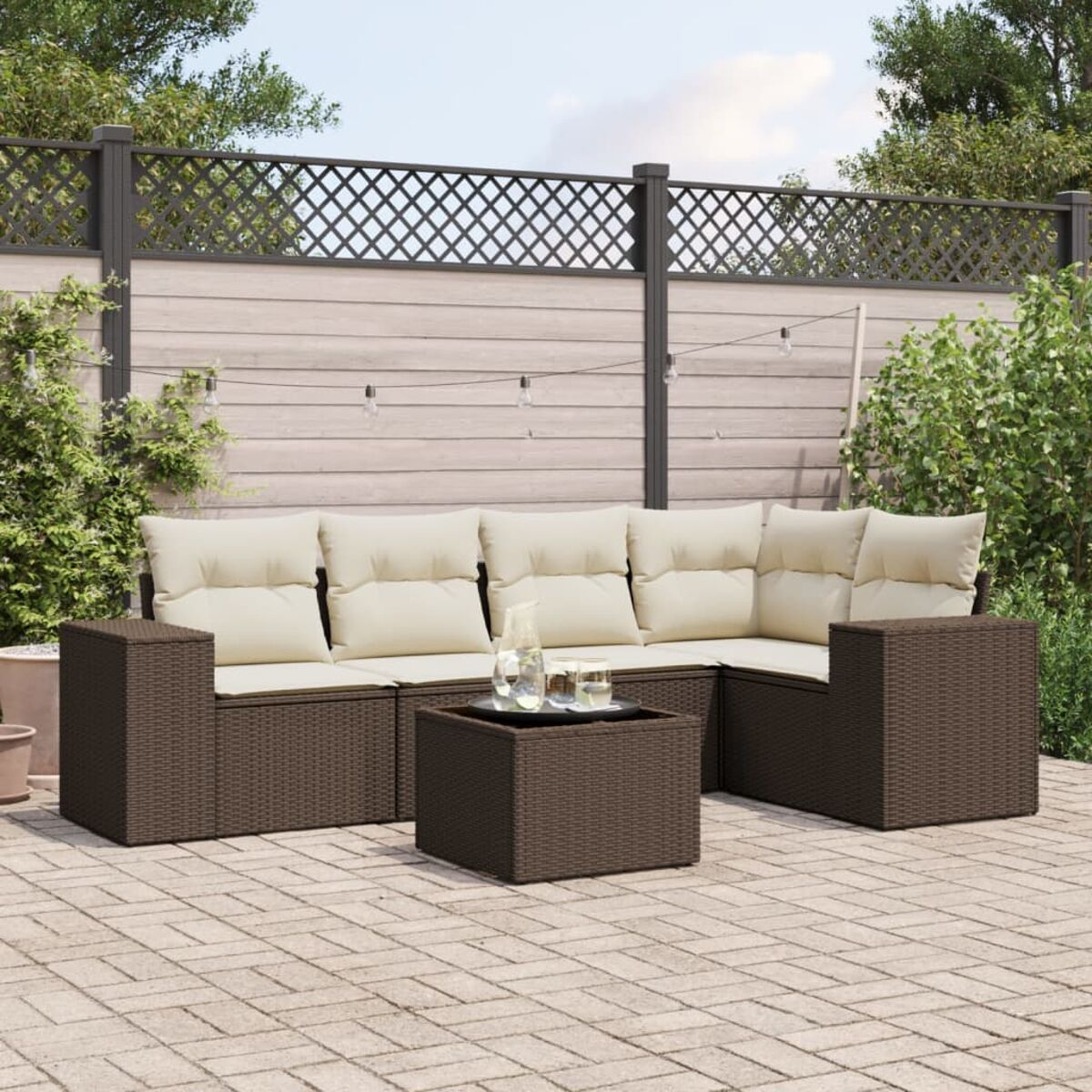Braunes Rattan-Terrassenmöbel-Set mit weißen Kissen.