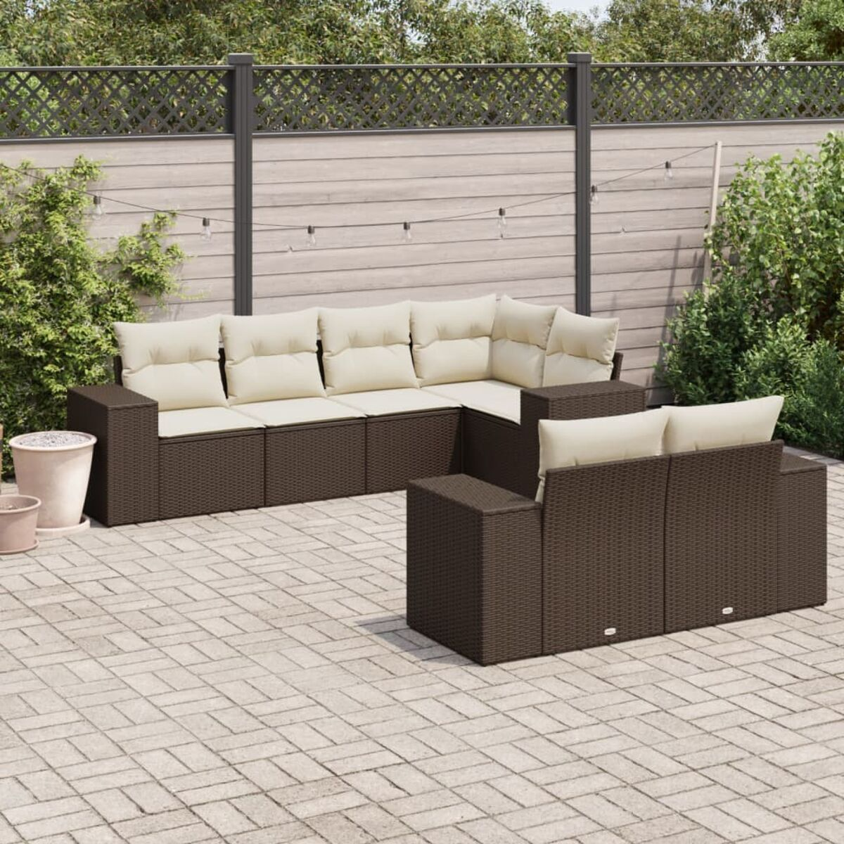 Outdoor-Möbelset aus braunem Korbgeflecht mit cremefarbenen Kissen. Es umfasst ein Sofa, einen Stuhl und einen Tisch.