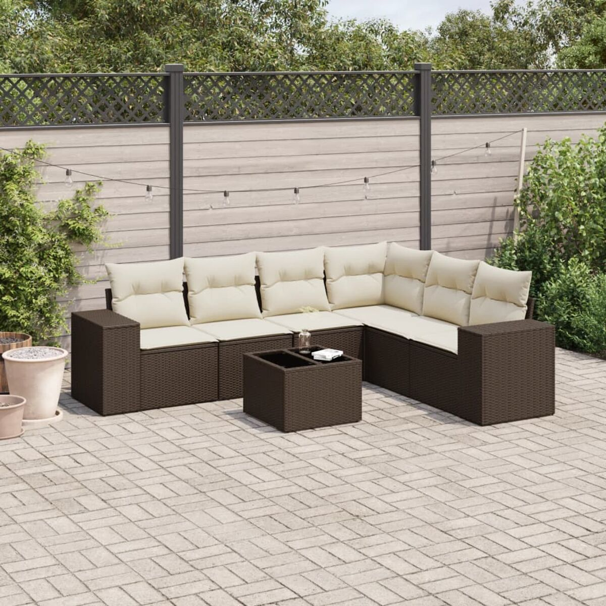 Un set di divani in rattan marrone su un patio in mattoni, con tavolo e cuscini color crema.