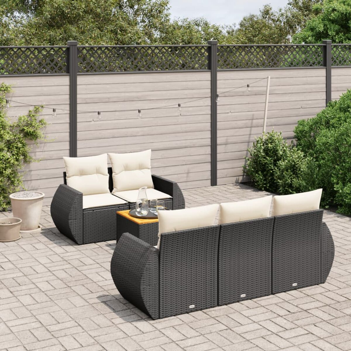 Gartenmöbel-Set auf der Terrasse. Bestehend aus Sofa, zwei Stühlen und Tisch, vor Holzzaun.