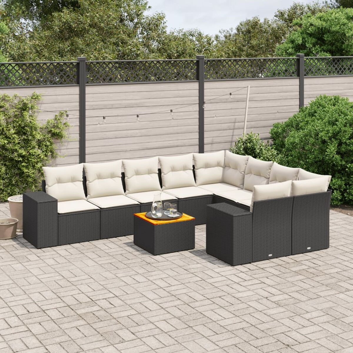 Outdoor-Geflecht-Sofagarnitur mit beigen Kissen, Tisch mit Gläsern, auf einer Terrasse.