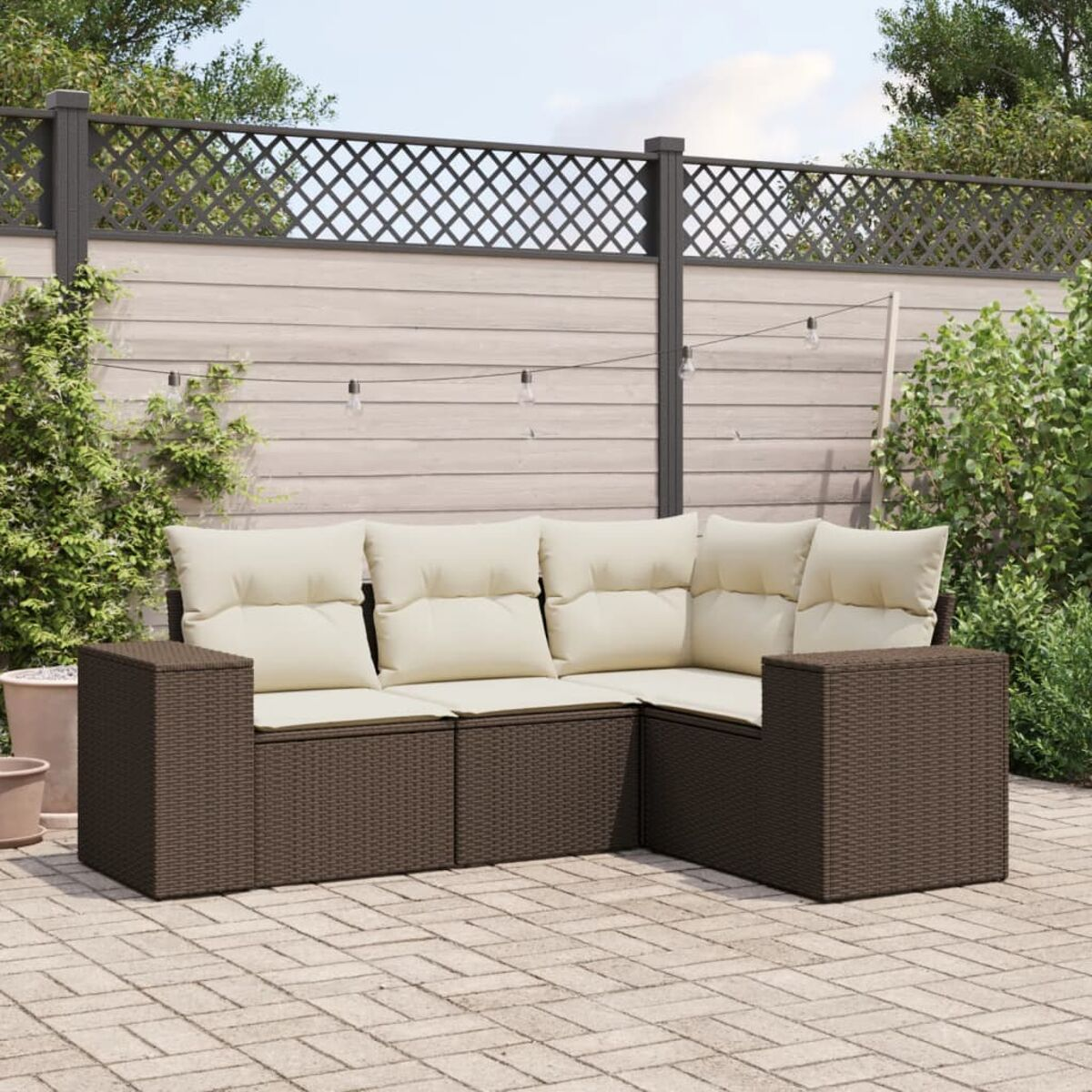 Divano componibile da esterno marrone con cuscini beige su un patio, con una recinzione e piante sullo sfondo.