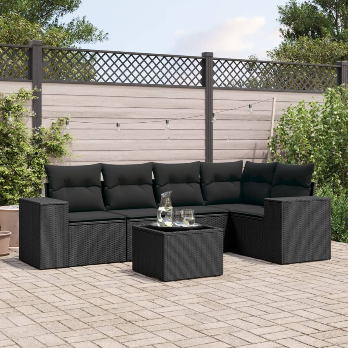 Schwarzes Outdoor-Ecksofa mit Couchtisch auf einer Ziegelterrasse.