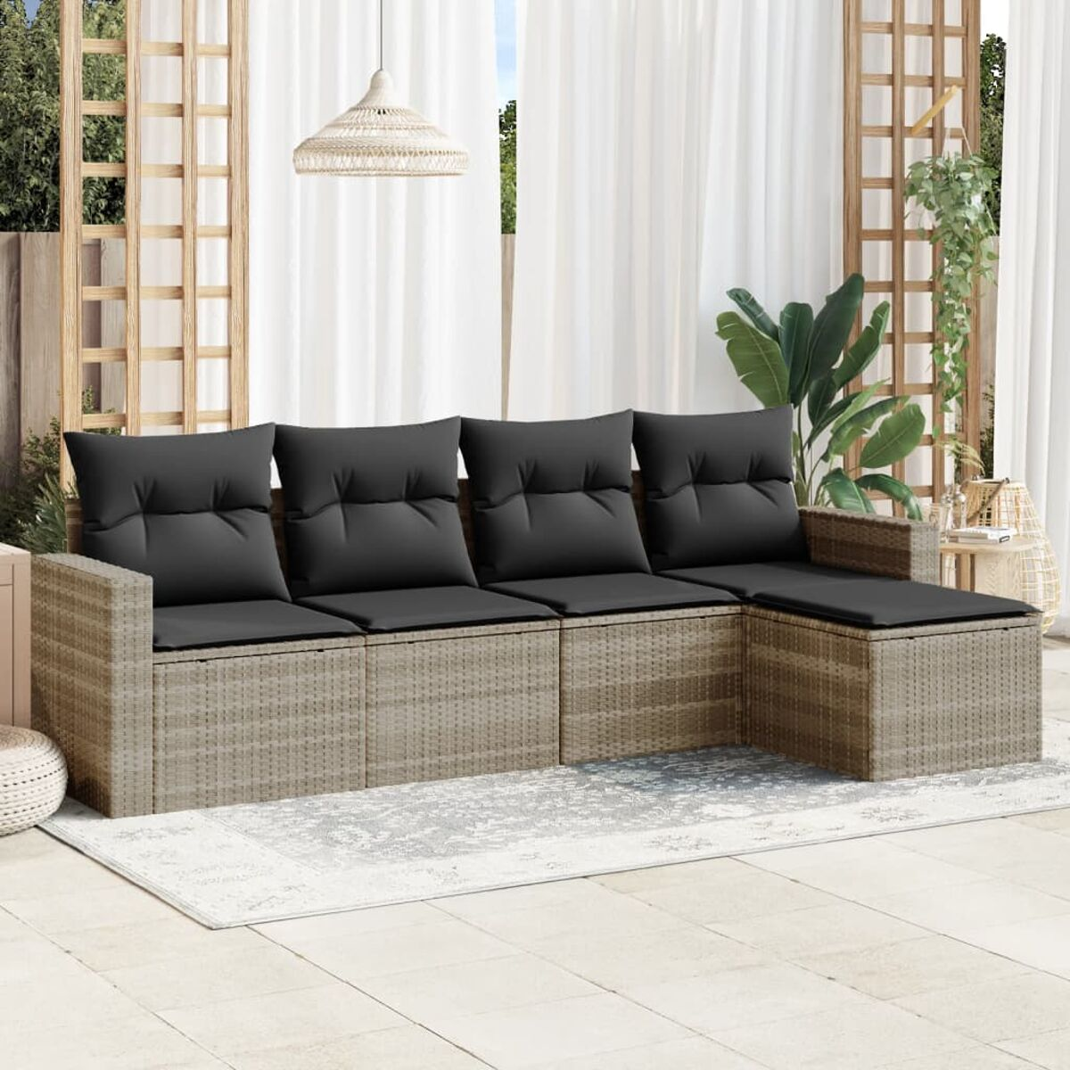 Divano in vimini beige con cuscini grigi su un patio, con tende e tappeto.