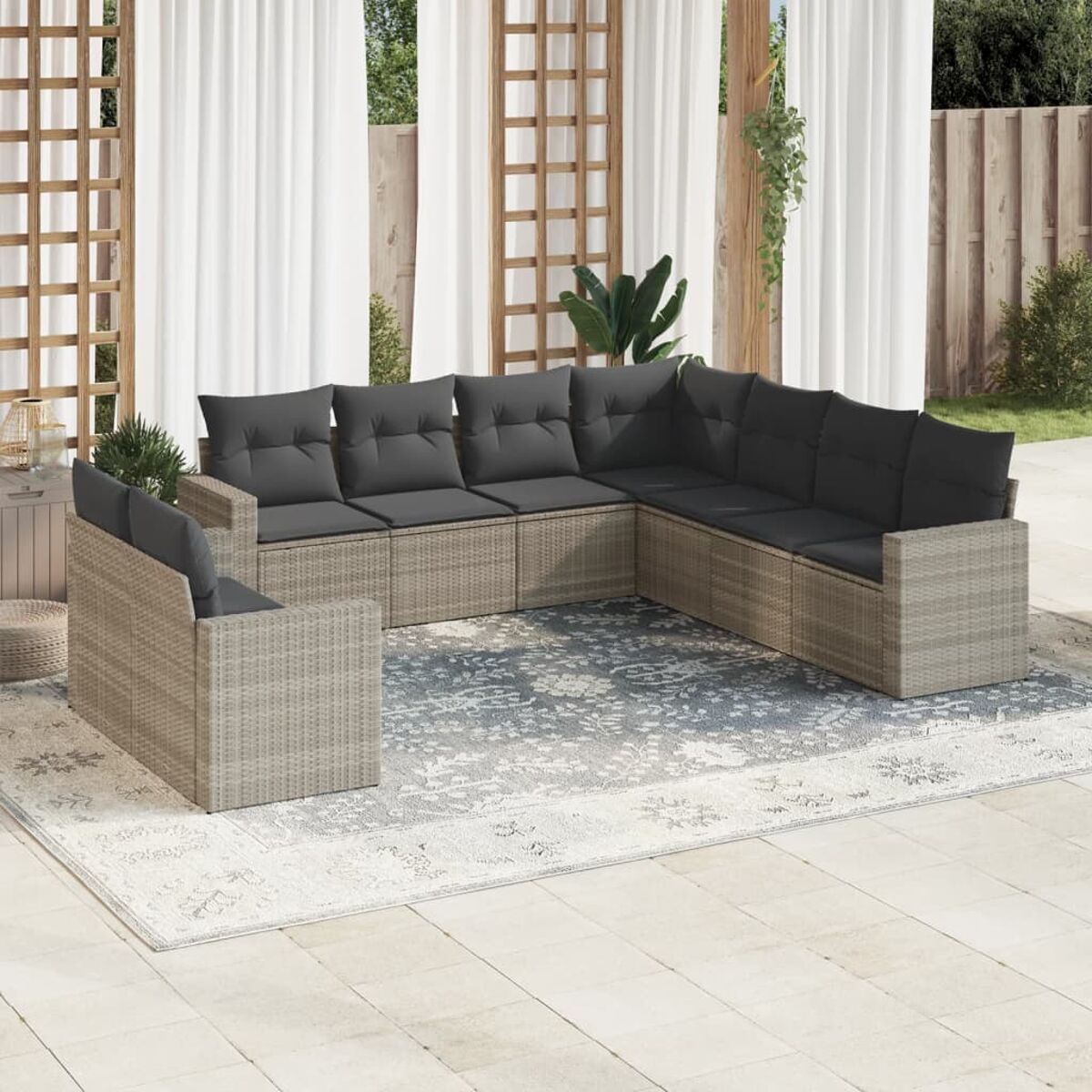 Outdoor-Ecksofa, hellbraunes Korbgeflecht mit grauen Kissen, auf einem gemusterten Teppich, mit Vorhängen im Hintergrund.