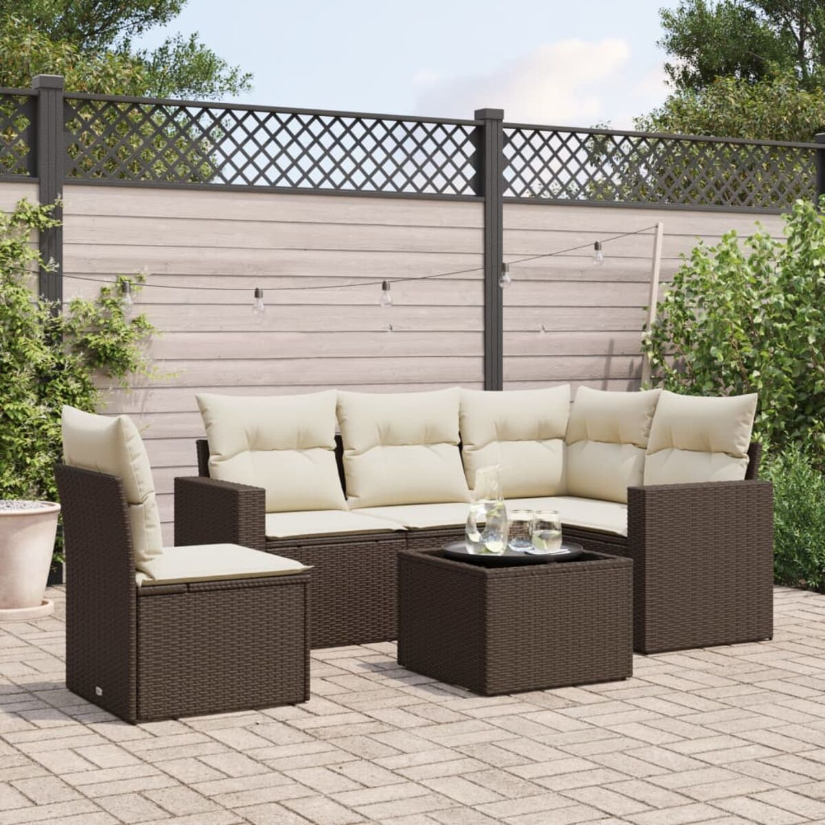 Ein braunes Outdoor-Möbelset aus Korbgeflecht mit Sofa, zwei Sesseln und Tisch mit Gläsern.