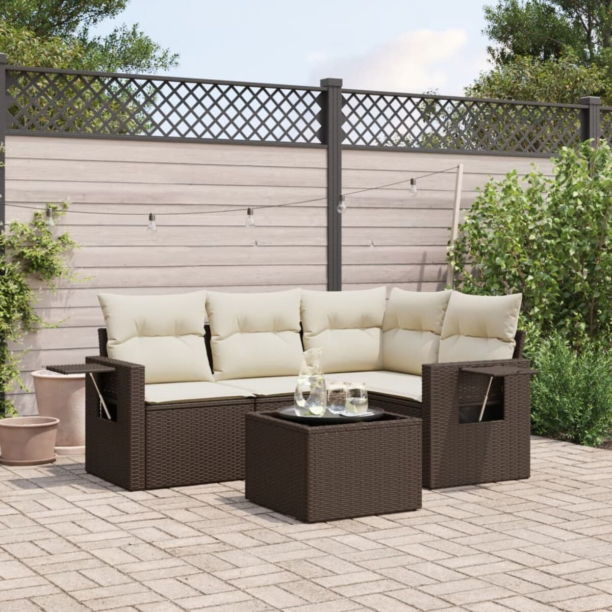 Divano componibile marrone con cuscini beige, tavolo e bevande su un patio.