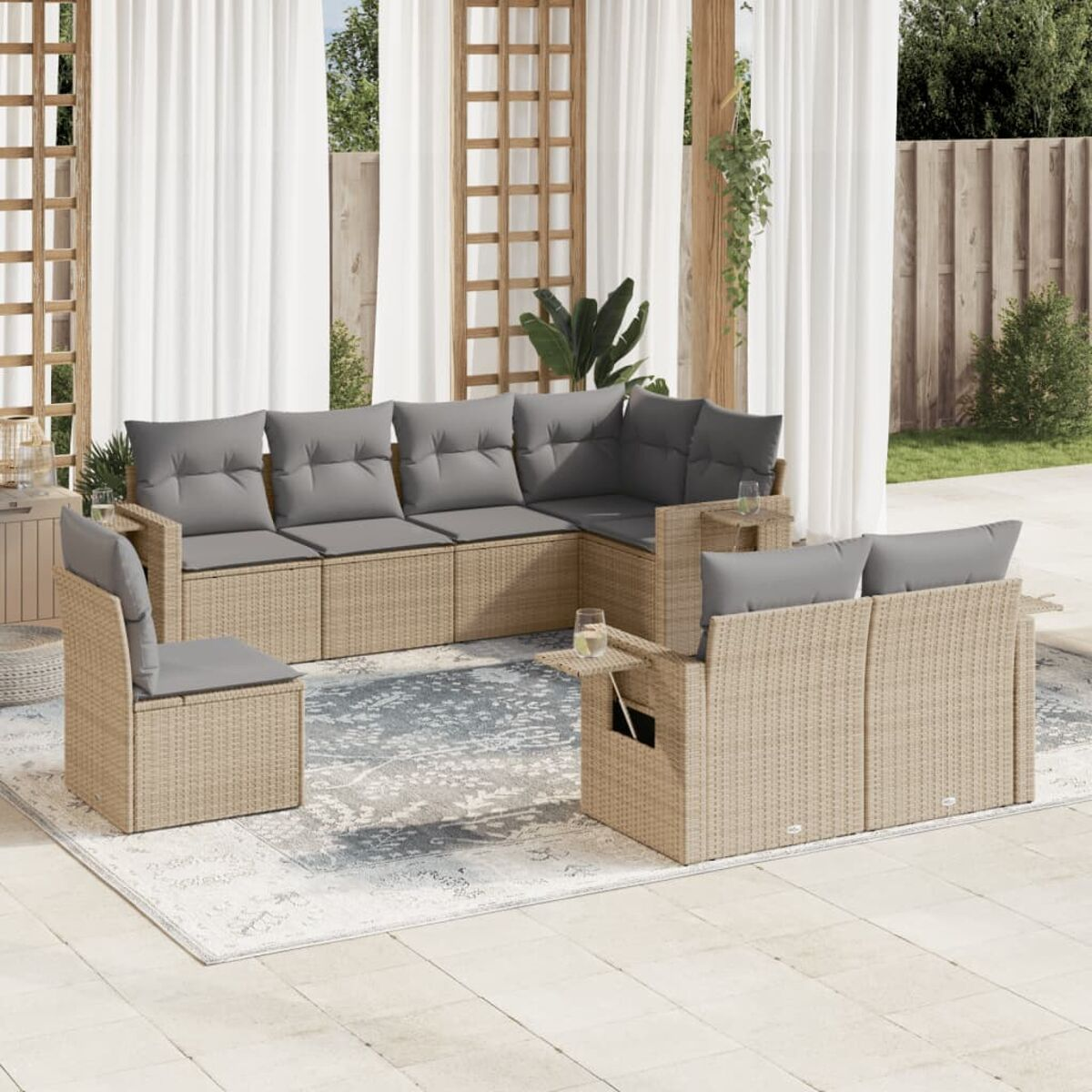 Geflochtenes Ecksofa mit grauen Kissen und Beistelltischen auf einer Terrasse. Vorhänge im Hintergrund.