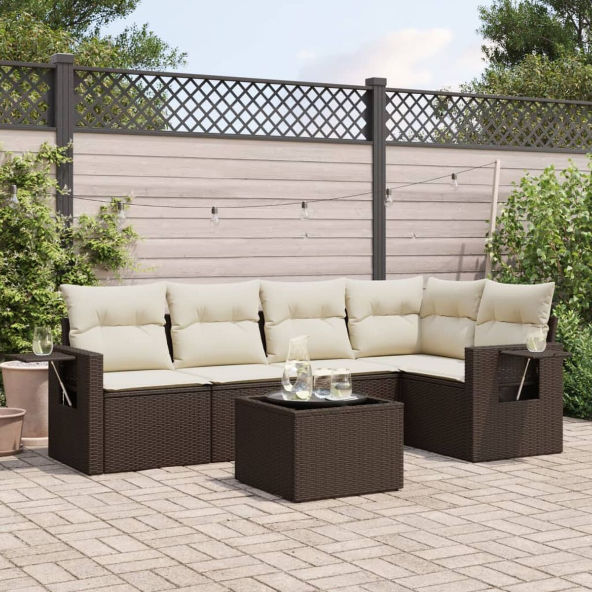 Set di mobili da esterno con divano componibile in rattan marrone, cuscini beige e tavolino.