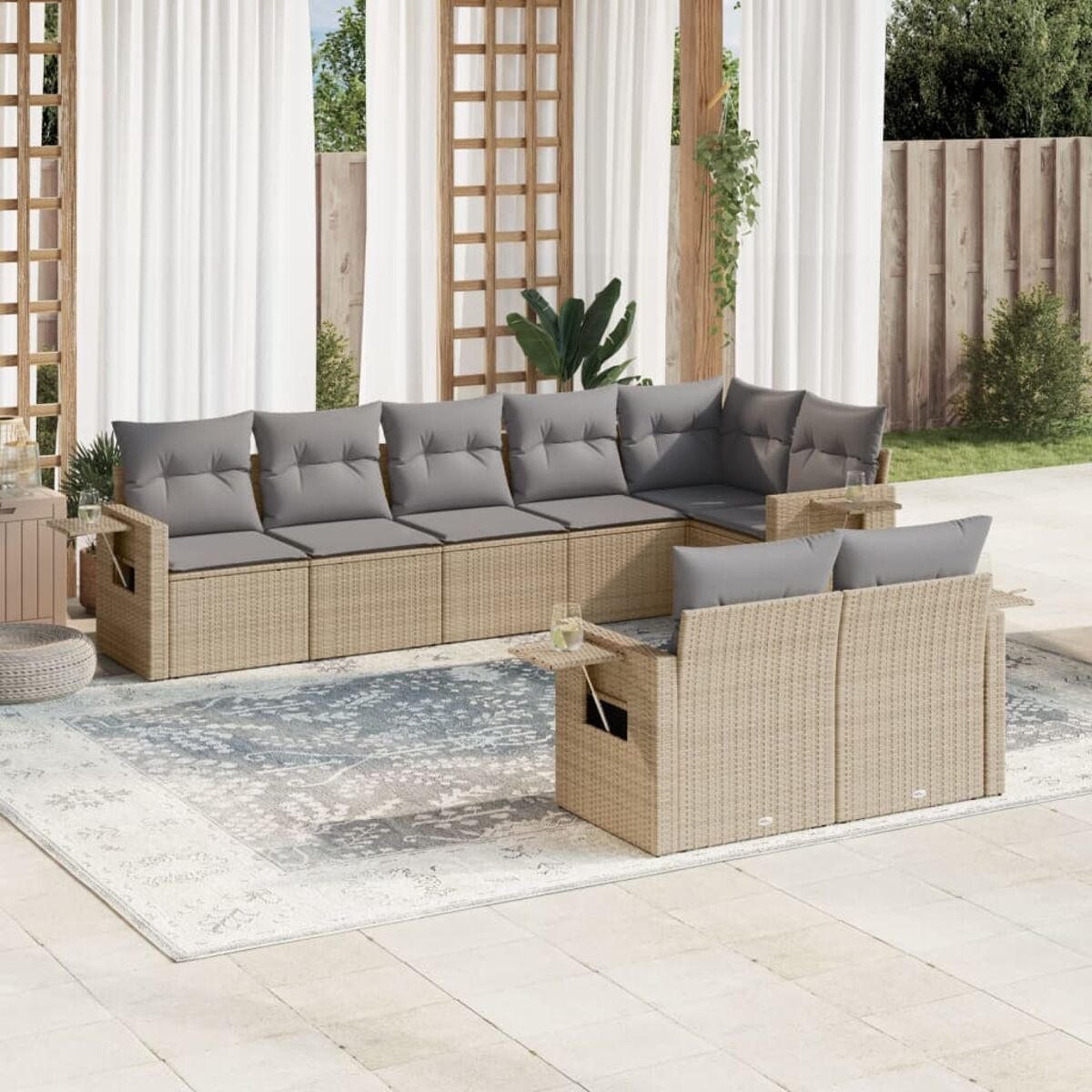 Ein beiges Rattan-Ecksofa-Set mit grauen Kissen und einem Tisch auf einem gemusterten Teppich.
