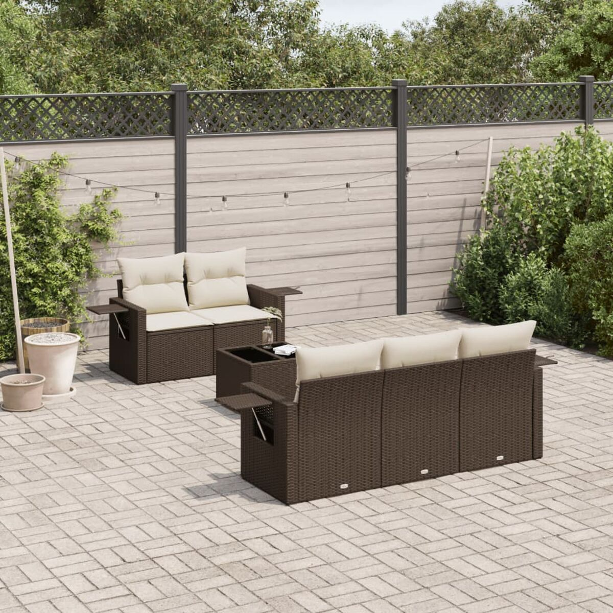 Set patio esterno con divano in rattan, tavolo e patio in mattoni. Set marrone con cuscini color crema.