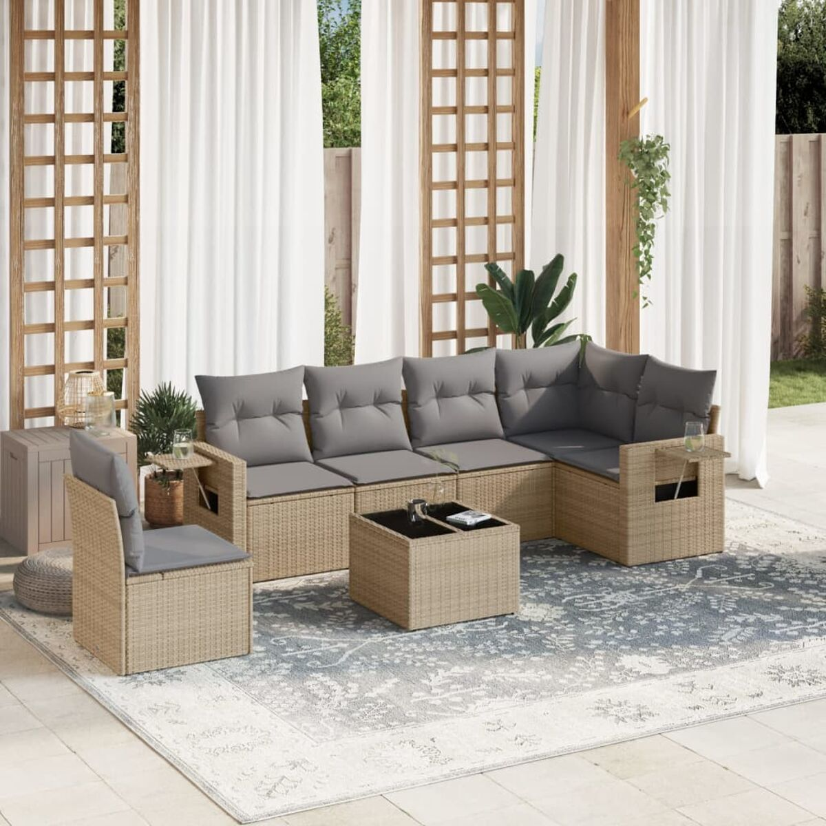 Beiges Outdoor-Ecksofa aus Korbgeflecht mit grauen Kissen, einem Tisch und einem Stuhl auf einem Teppich.