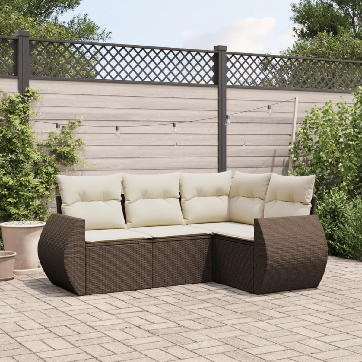 Geflecht-Terrassenmöbel mit cremefarbenen Kissen. Ziegel-Patio mit Grün im Hintergrund.