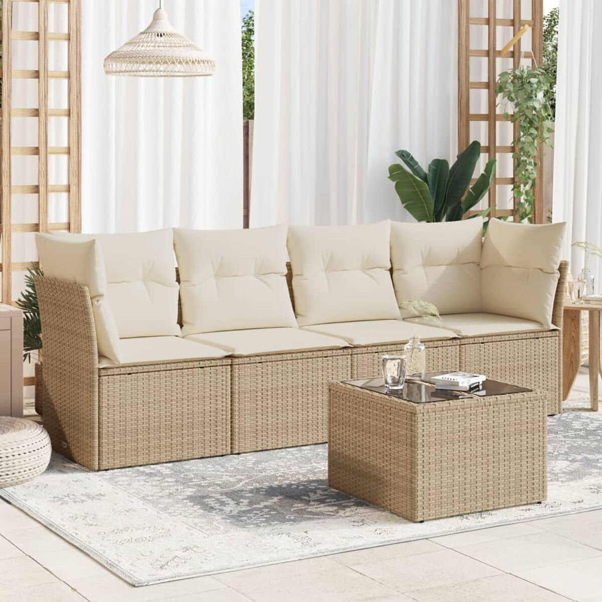 Beiges Korbsessel-Outdoor-Set mit cremefarbenen Kissen. Couchtisch mit Glasplatte. Weiße Vorhänge im Hintergrund.