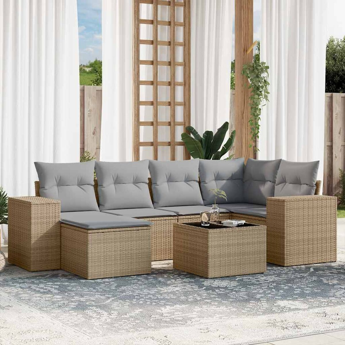 Rattansofa-Set mit grauen Kissen. Inklusive Couchtisch. Außenbereich mit Vorhängen.