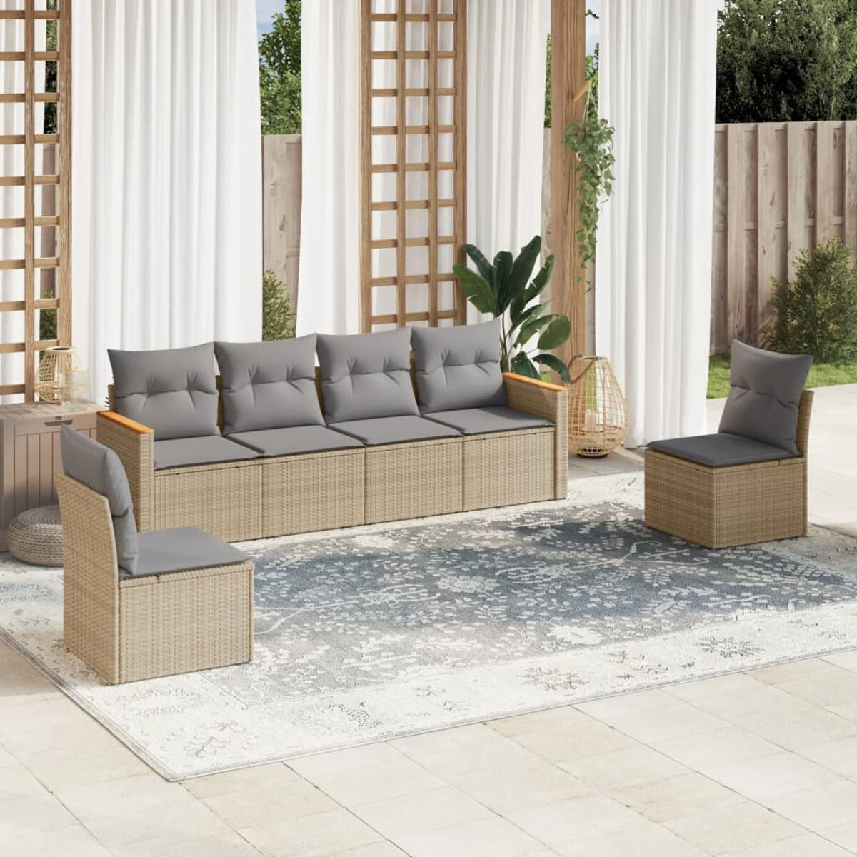 Terrassenset im Freien mit hellbraunen Korbmöbeln, grauen Kissen und einem gemusterten Teppich. Weiße Vorhänge im Hintergrund.