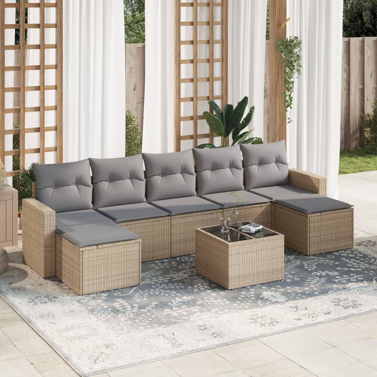 Beiges Ecksofa aus Korbgeflecht mit grauen Kissen und einem Couchtisch, auf einem gemusterten Teppich.