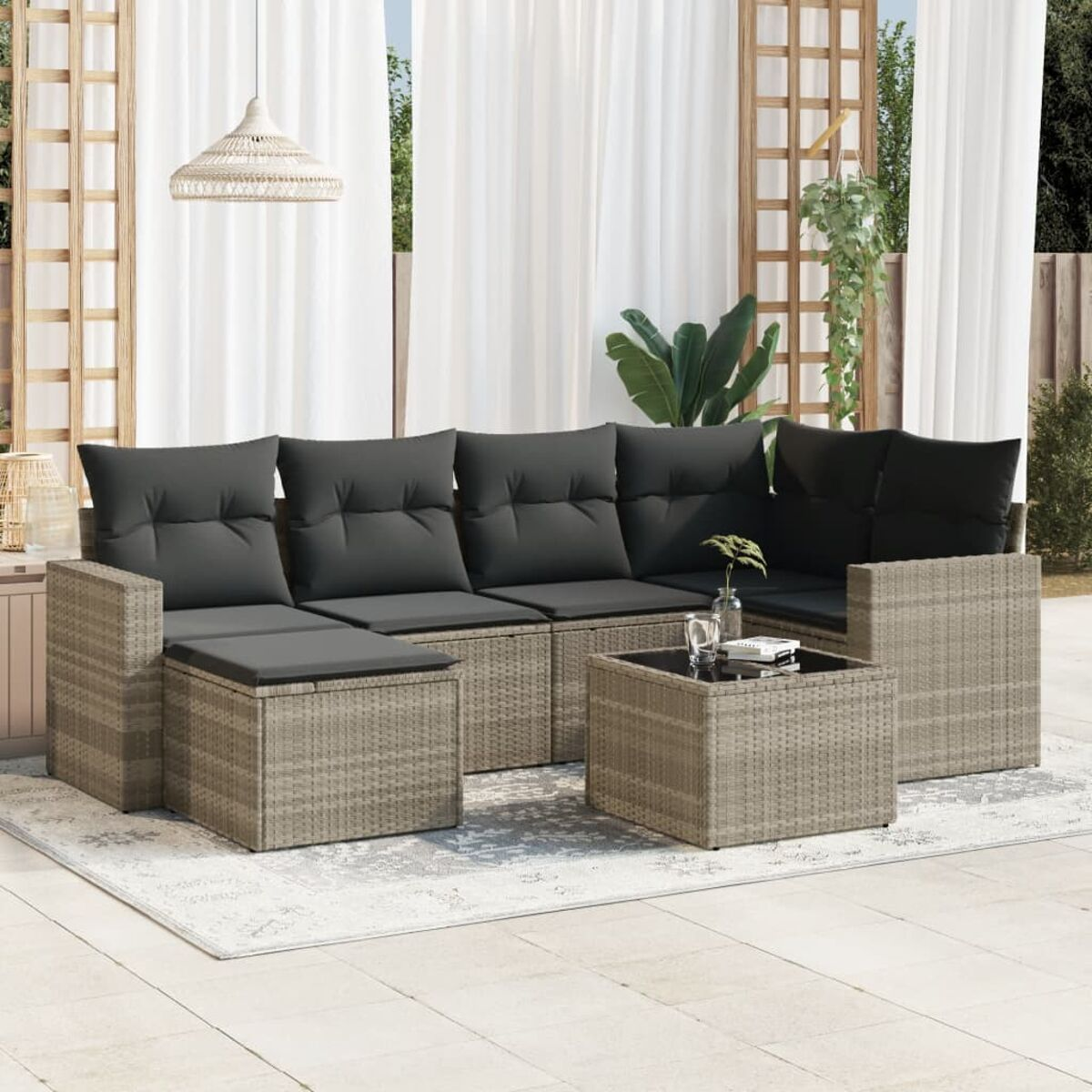 Graues Ecksofa aus Korbgeflecht mit Couchtisch, Teppich und weißen Vorhängen.