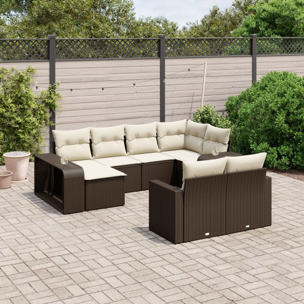Set di mobili da patio esterno in vimini marrone con cuscini color crema, cortile soleggiato.