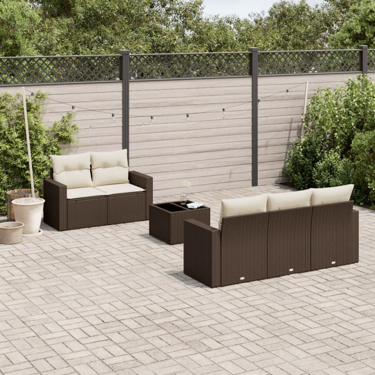 Set divani in rattan marrone con cuscini crema e tavolo sul patio.