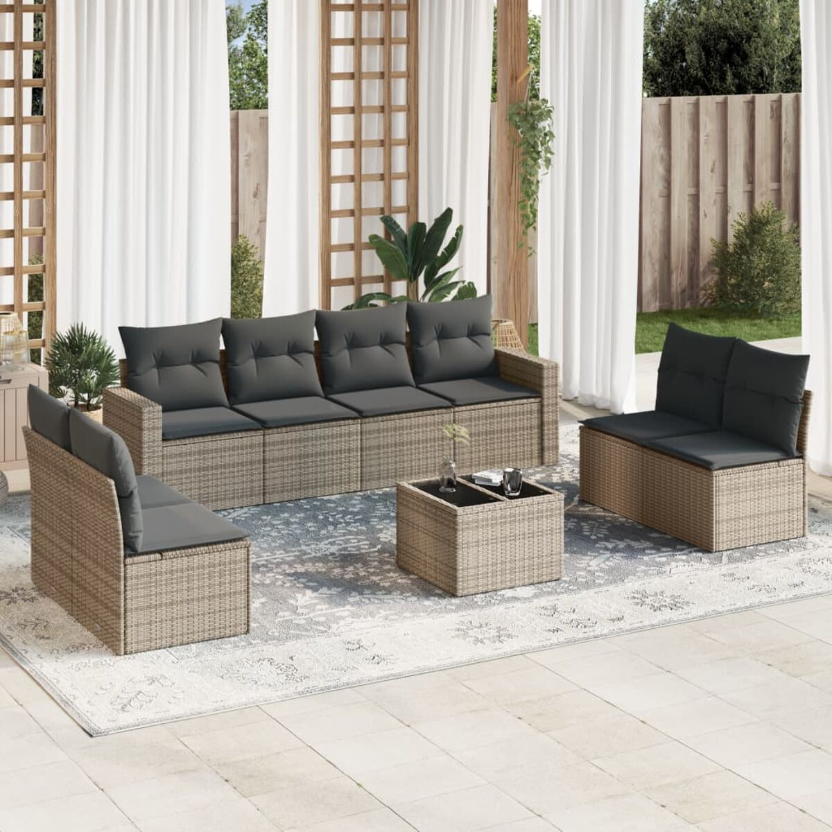 Terrassenmöbel-Set im Freien auf einem grauen Teppich. Enthält ein Sofa, zwei Stühle und einen Couchtisch. Weiße Vorhänge.